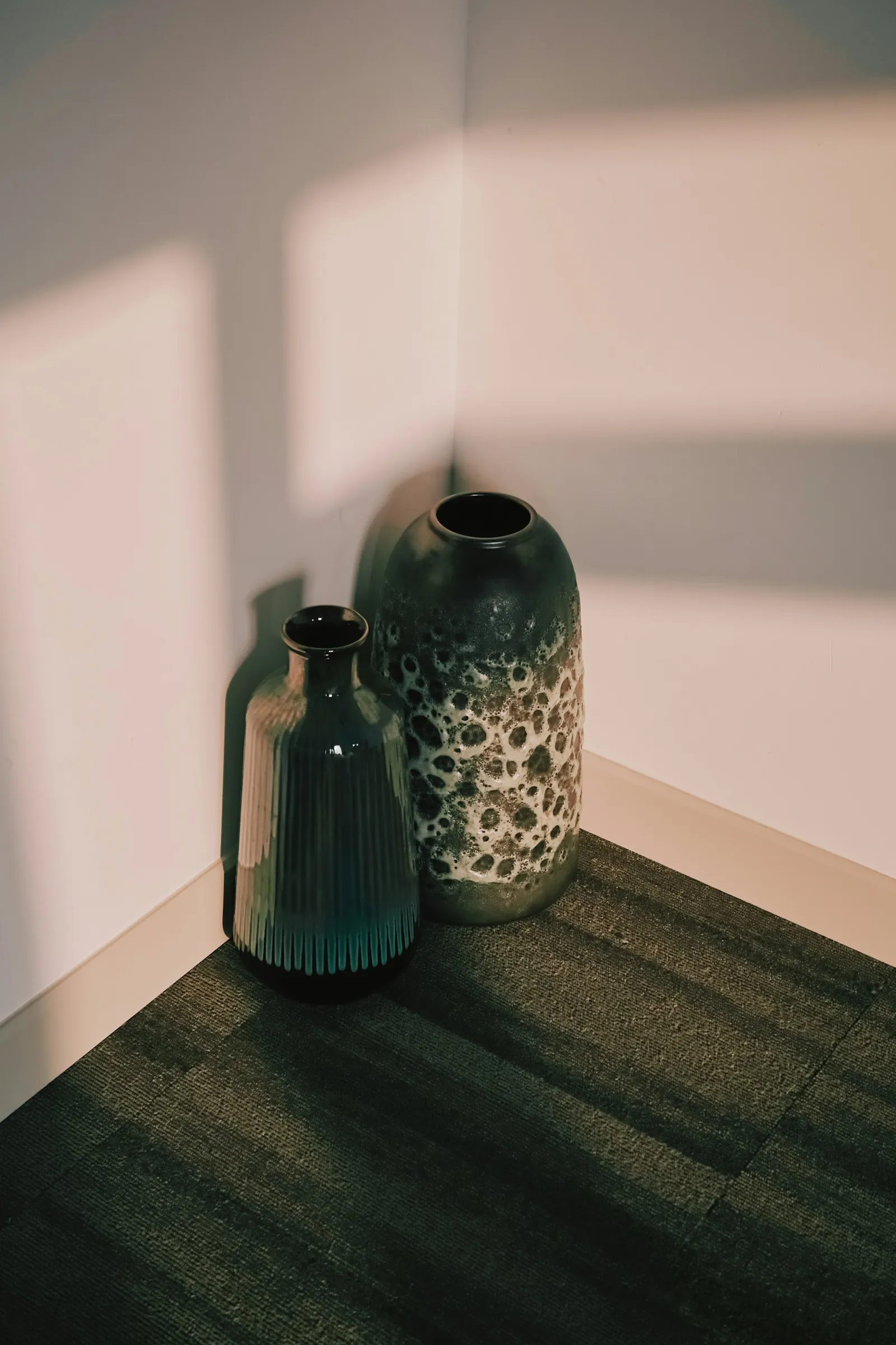 Două vase ceramice într-un colț luminat de soare, cu umbre moi. Imagine demonstrativă.